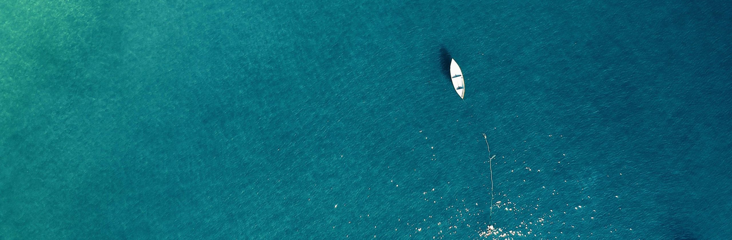 Aerial view of a lone boat on calm turquoise waters, showcasing tranquility.