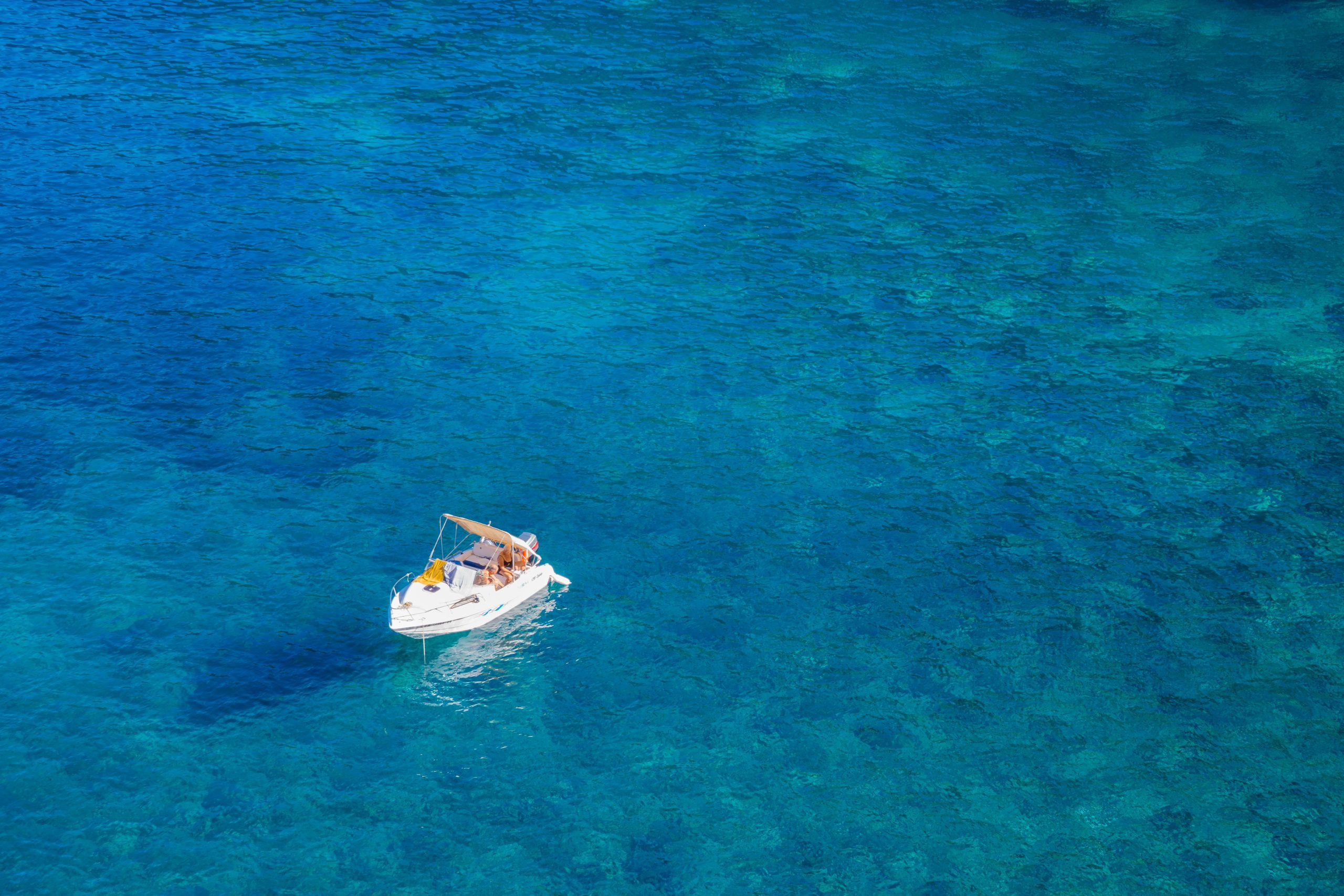 Aerial shot of a white boat floating on clear turquoise waters in Mallorca, Spain, perfect for travel and leisure.