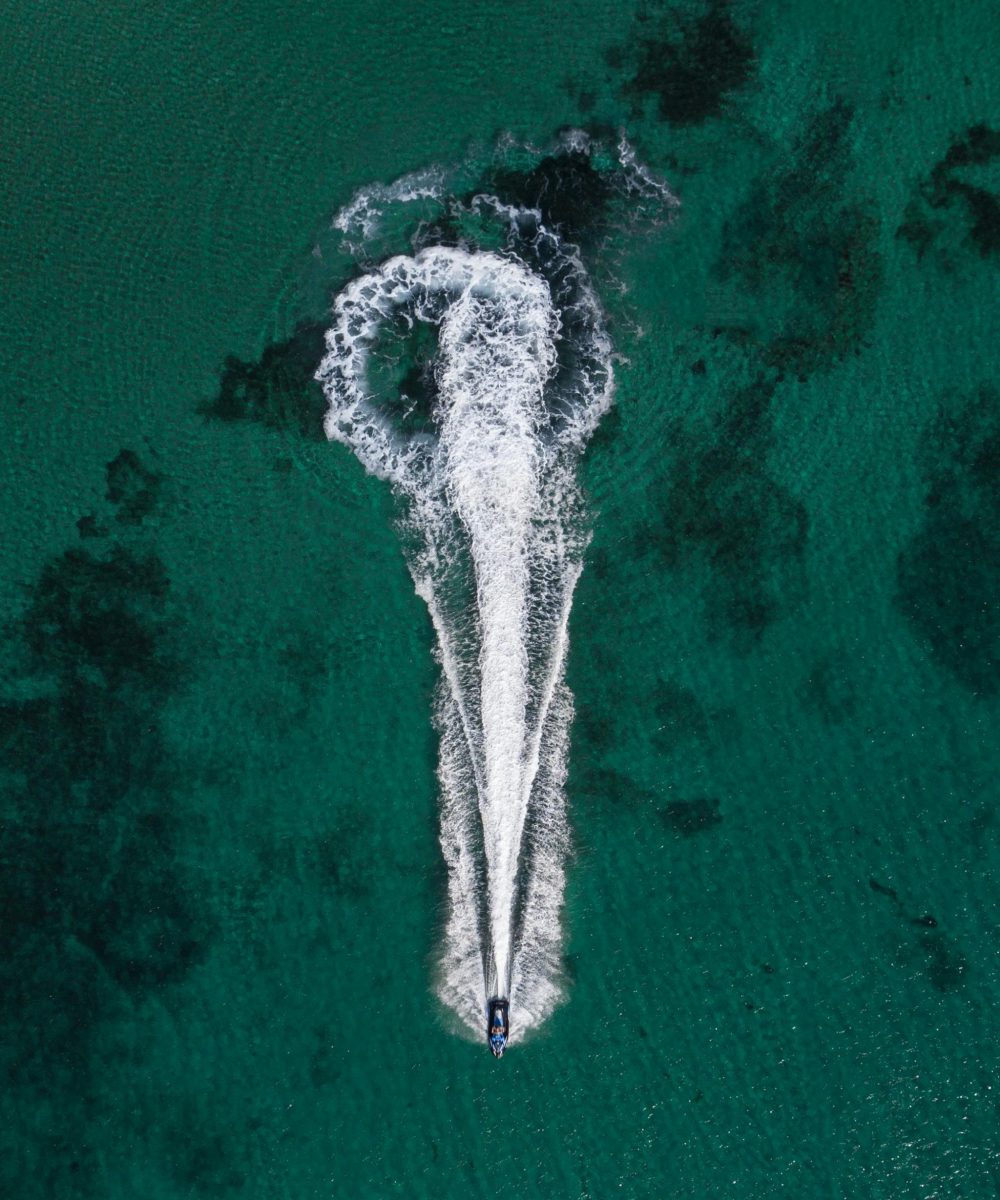 Stunning aerial photograph of a boat creating a wake in the turquoise waters of Melbourne, Australia.