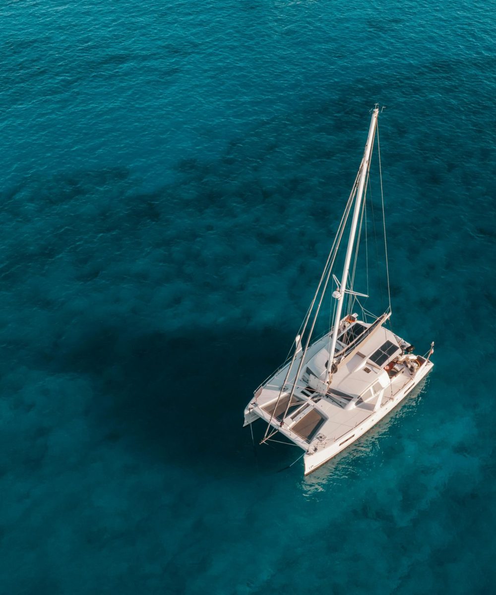 A serene aerial shot of a catamaran sailing on crystal blue waters, perfect for travel and marine themes.