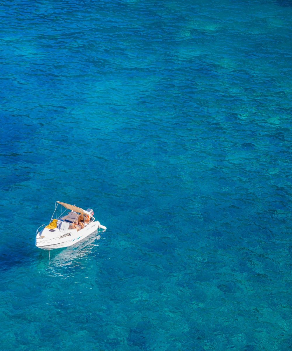 Aerial shot of a white boat floating on clear turquoise waters in Mallorca, Spain, perfect for travel and leisure.